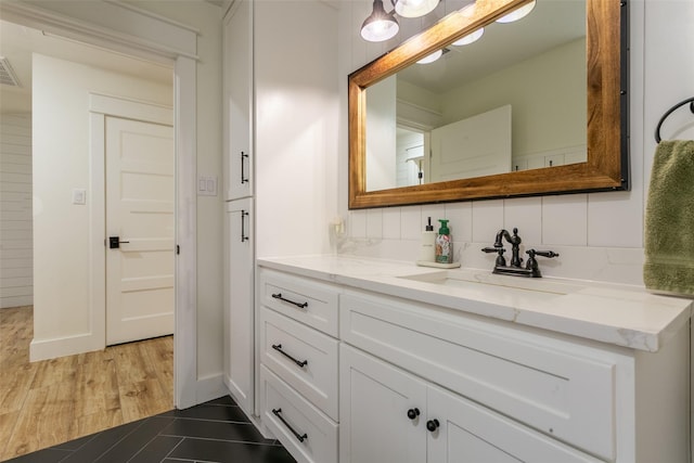bathroom featuring baseboards, visible vents, decorative backsplash, and vanity