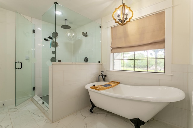 full bath featuring a freestanding bath, a chandelier, marble finish floor, tile walls, and a shower stall