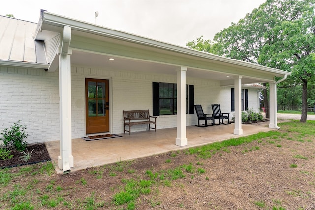 back of property featuring brick siding, metal roof, a standing seam roof, and a porch