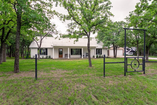 rear view of house featuring fence, covered porch, a lawn, and metal roof