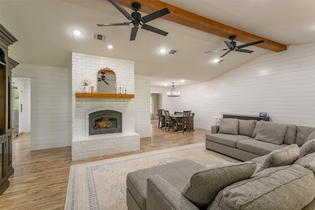 living room with visible vents, a fireplace, lofted ceiling with beams, ceiling fan with notable chandelier, and light wood-style floors