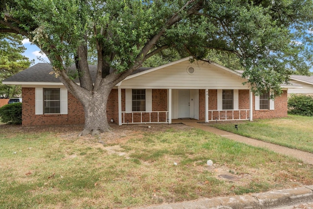 view of front of house featuring brick siding, covered porch, and a front yard