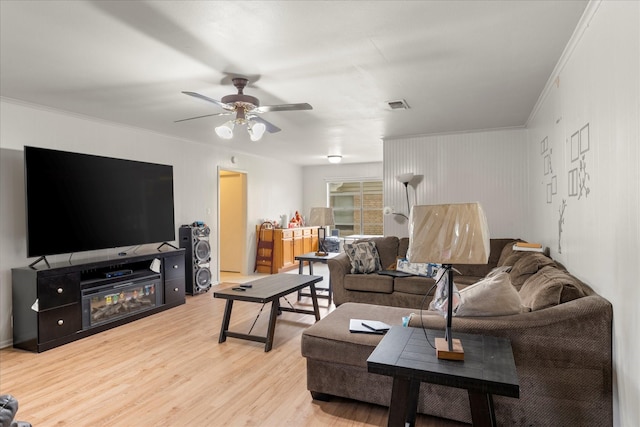 living area featuring visible vents, ornamental molding, ceiling fan, and light wood-type flooring