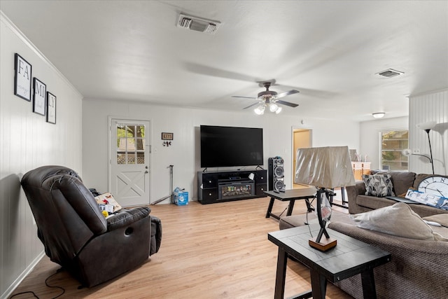 living area featuring visible vents, crown molding, light wood-style flooring, and ceiling fan
