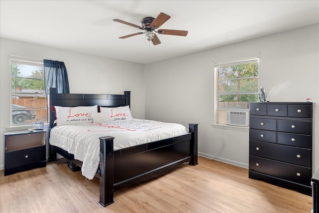 bedroom featuring baseboards, a ceiling fan, light wood finished floors, and multiple windows