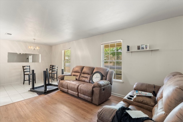 living room featuring visible vents, baseboards, wood finished floors, and a chandelier