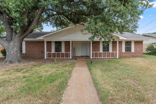 single story home with covered porch, brick siding, a shingled roof, and a front yard