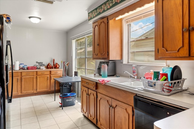 kitchen featuring light countertops, light tile patterned floors, brown cabinetry, and black appliances