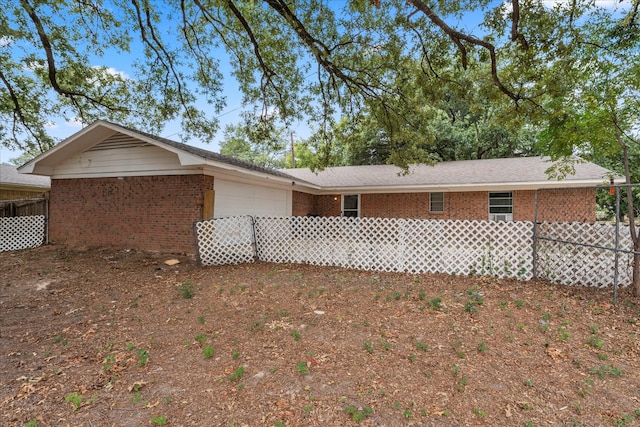 exterior space with brick siding, an attached garage, and fence