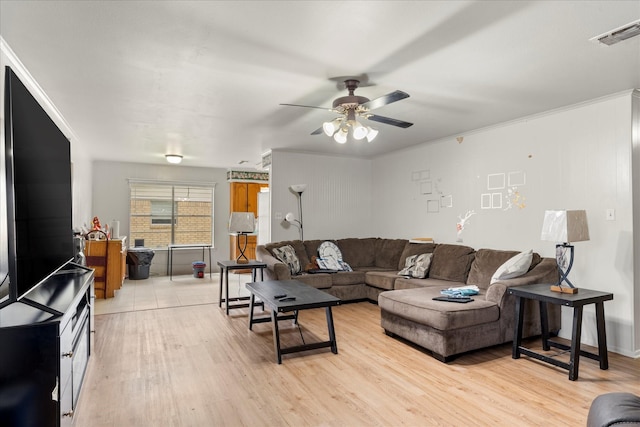living room with crown molding, ceiling fan, light wood-type flooring, and visible vents