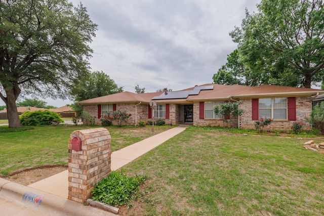 ranch-style house with roof mounted solar panels, brick siding, and a front yard