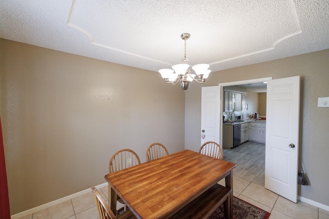 dining room with light tile patterned floors, baseboards, a textured ceiling, and a notable chandelier