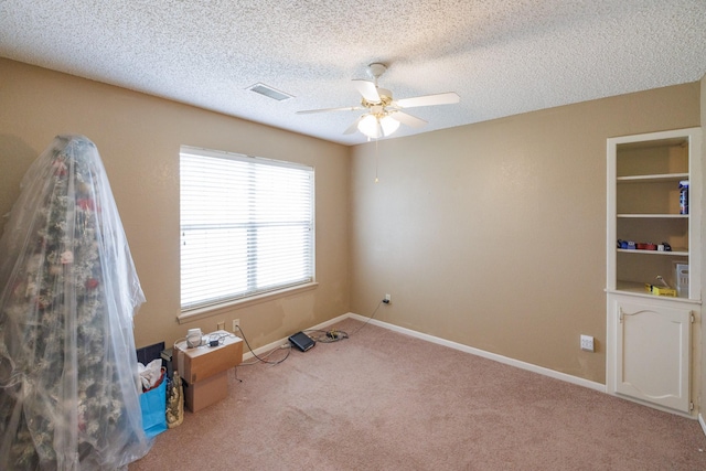 spare room featuring visible vents, a textured ceiling, ceiling fan, and carpet floors
