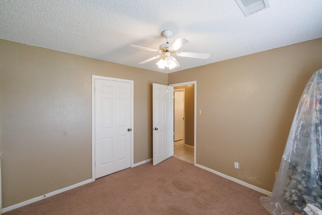 unfurnished bedroom featuring carpet flooring, ceiling fan, a textured ceiling, baseboards, and visible vents