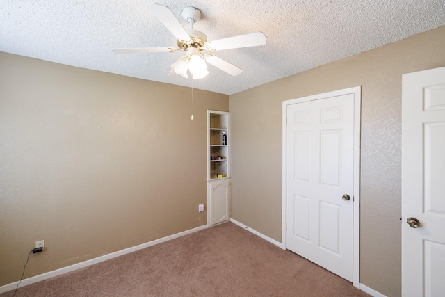 empty room featuring baseboards, ceiling fan, light carpet, and a textured ceiling