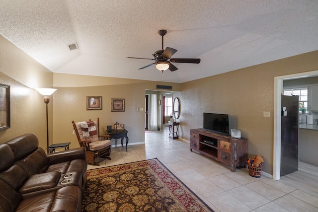 living area featuring light tile patterned floors, ceiling fan, a textured ceiling, and visible vents