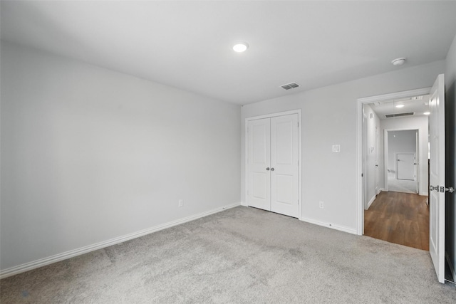 unfurnished bedroom with attic access, visible vents, baseboards, a closet, and carpet