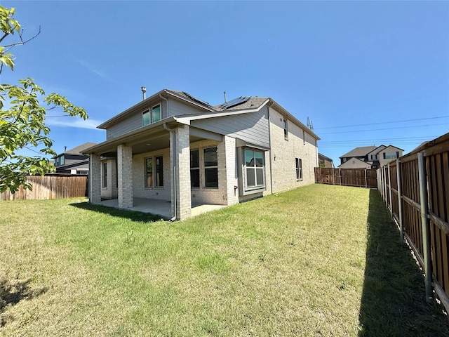 421 Acton Ave, Fort Worth, TX 76131 - back of house featuring brick siding, a fenced backyard, roof mounted solar panels, and a patio