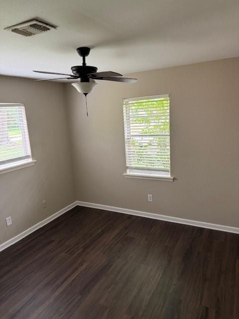 unfurnished room featuring a ceiling fan, baseboards, visible vents, and dark wood-type flooring