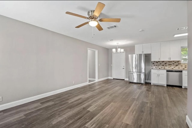 unfurnished living room with baseboards, ceiling fan with notable chandelier, dark wood-style flooring, and visible vents