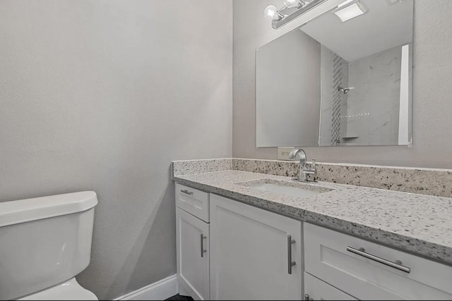 bathroom featuring vanity, walk in shower, and toilet