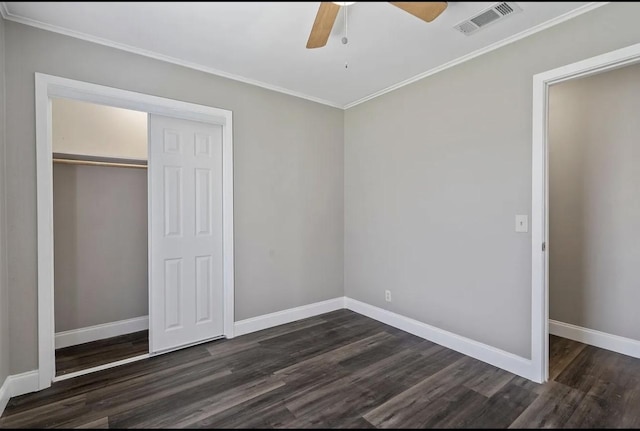 unfurnished bedroom with crown molding, dark wood-style flooring, baseboards, and a closet