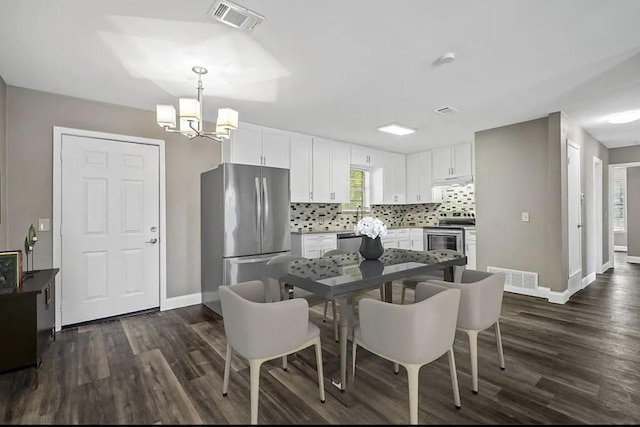 dining space with visible vents, dark wood-type flooring, and a notable chandelier