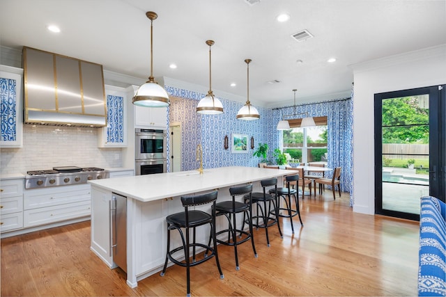 kitchen with appliances with stainless steel finishes, a sink, light countertops, visible vents, and ornamental molding