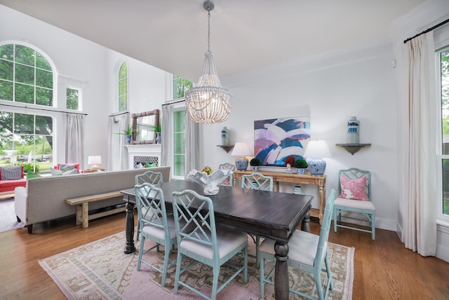 dining area featuring an inviting chandelier, wood finished floors, and a fireplace