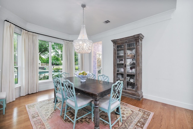 dining room featuring an inviting chandelier, light wood-style floors, crown molding, and visible vents