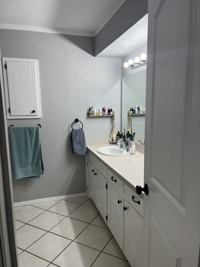 bathroom with tile patterned floors, ornamental molding, baseboards, and vanity