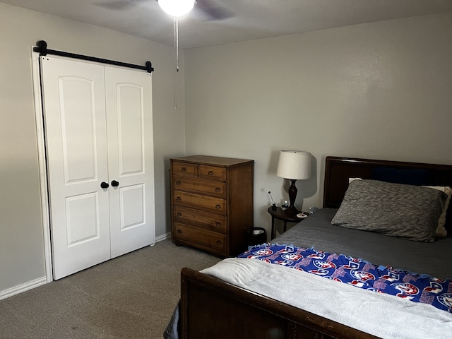 carpeted bedroom with baseboards, a ceiling fan, a closet, and a barn door