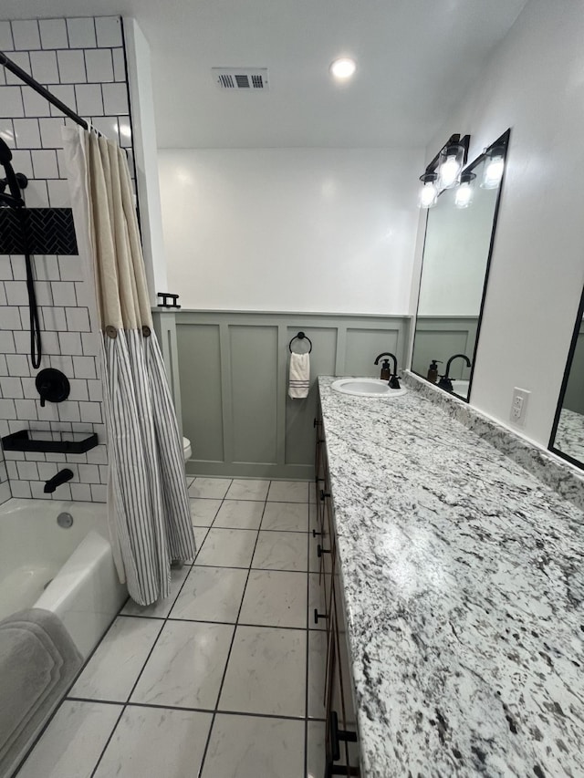 full bathroom with visible vents, shower / bath combination with curtain, vanity, a wainscoted wall, and marble finish floor