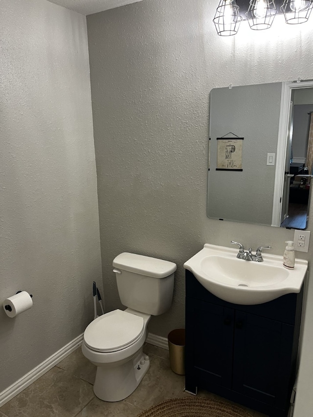 bathroom featuring vanity, tile patterned flooring, baseboards, and toilet
