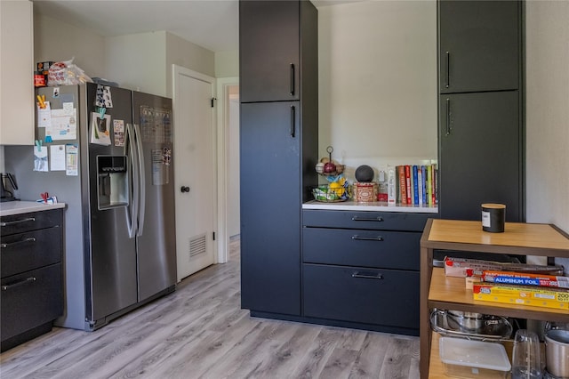 kitchen featuring light countertops, light wood finished floors, and stainless steel refrigerator with ice dispenser