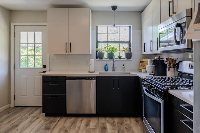 kitchen featuring dark cabinetry, a sink, plenty of natural light, and appliances with stainless steel finishes