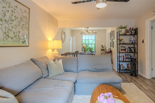 living area featuring baseboards, ceiling fan with notable chandelier, and wood finished floors
