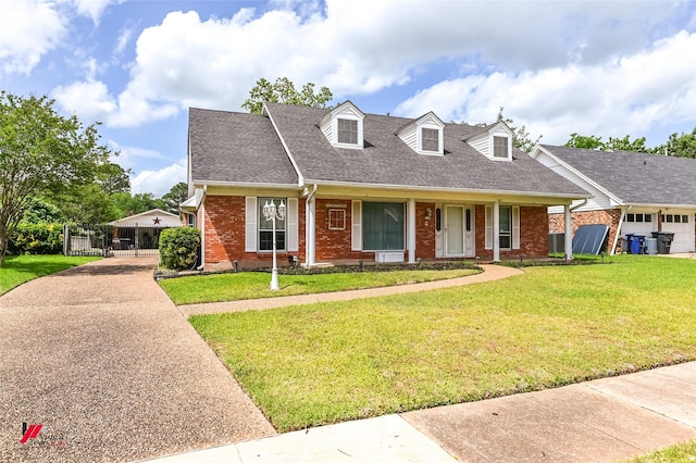 cape cod home with a shingled roof, a front yard, driveway, and brick siding