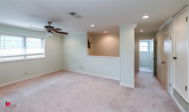 spare room with crown molding, light carpet, a ceiling fan, and visible vents