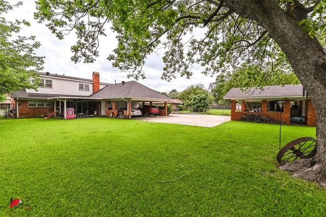 view of yard featuring fence, an attached carport, and driveway
