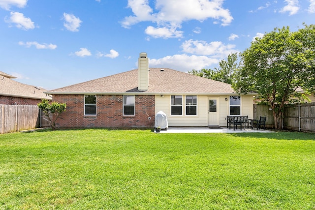 rear view of property featuring a lawn, a patio, a chimney, and a fenced backyard