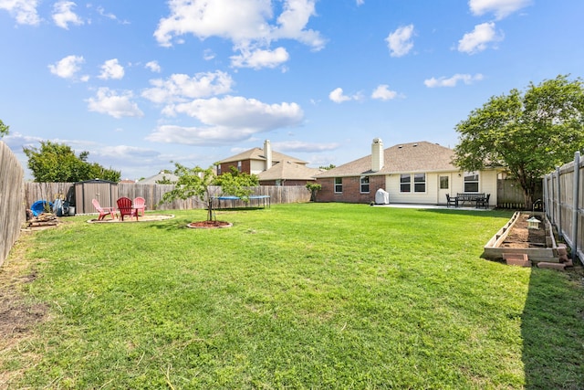 view of yard featuring a storage unit, a trampoline, a vegetable garden, a fenced backyard, and a patio area