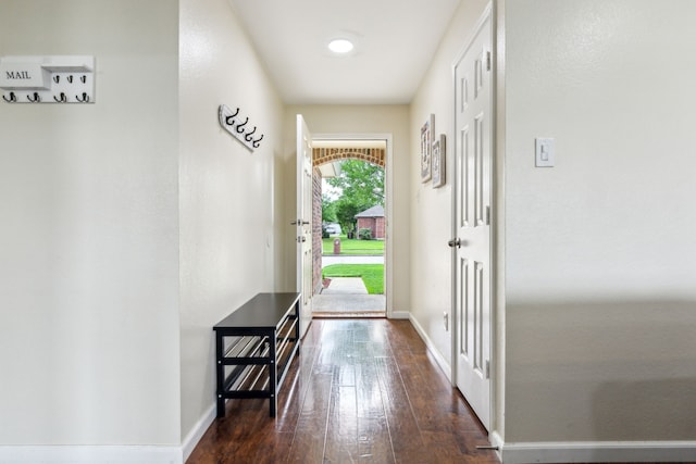 doorway to outside featuring baseboards and dark wood-style floors