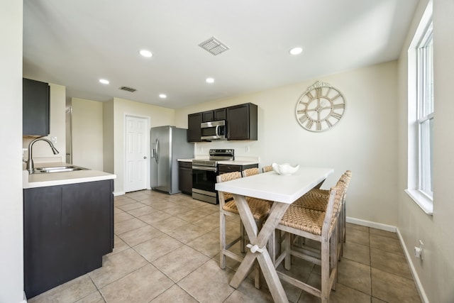 kitchen with light tile patterned flooring, appliances with stainless steel finishes, a sink, and visible vents