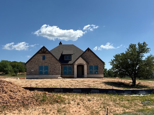 view of front of home featuring a chimney and brick siding