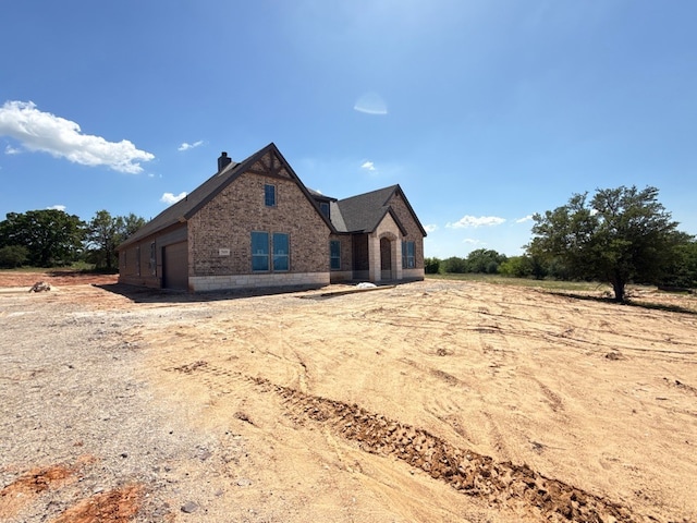 view of front of home featuring brick siding and a chimney