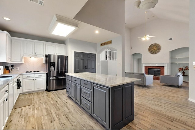 3017 Holford Rd, Richardson, TX 75082 - kitchen featuring stainless steel fridge, white cabinets, under cabinet range hood, a ceiling fan, and high vaulted ceiling