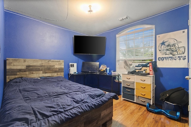 bedroom featuring visible vents, vaulted ceiling, and light wood-type flooring