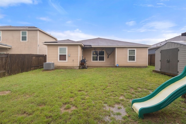 back of house with a playground, a storage shed, a fenced backyard, a lawn, and an outdoor structure