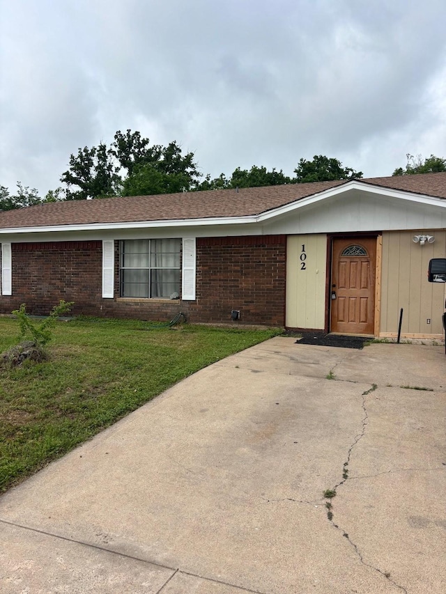 single story home with brick siding, a front yard, and concrete driveway